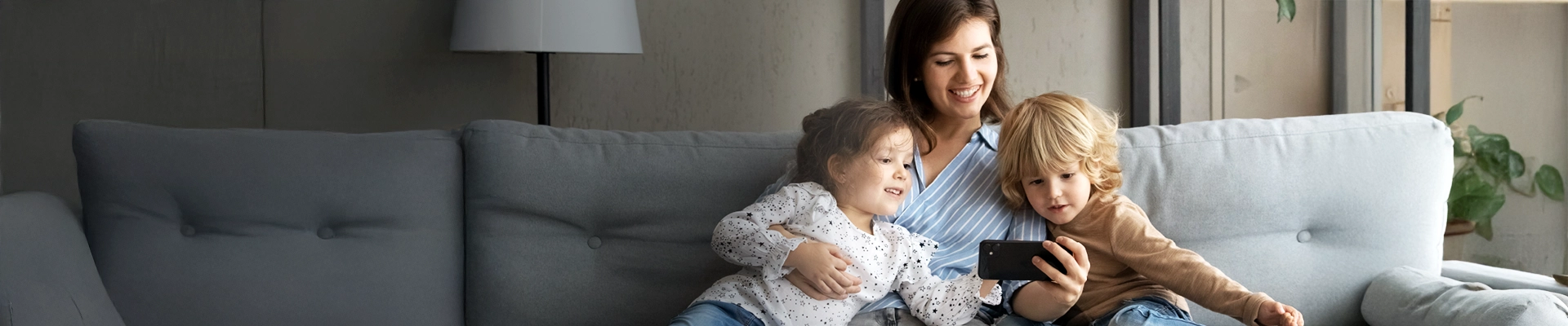 Image of mother with two young kids, enjoying Internet services on mobile phone CDE Lightband broadband